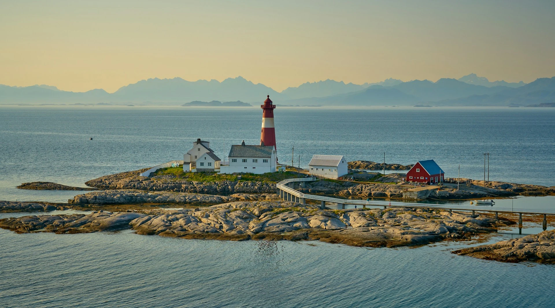 A norwegic island with soem houses and a lightpost at sunset.